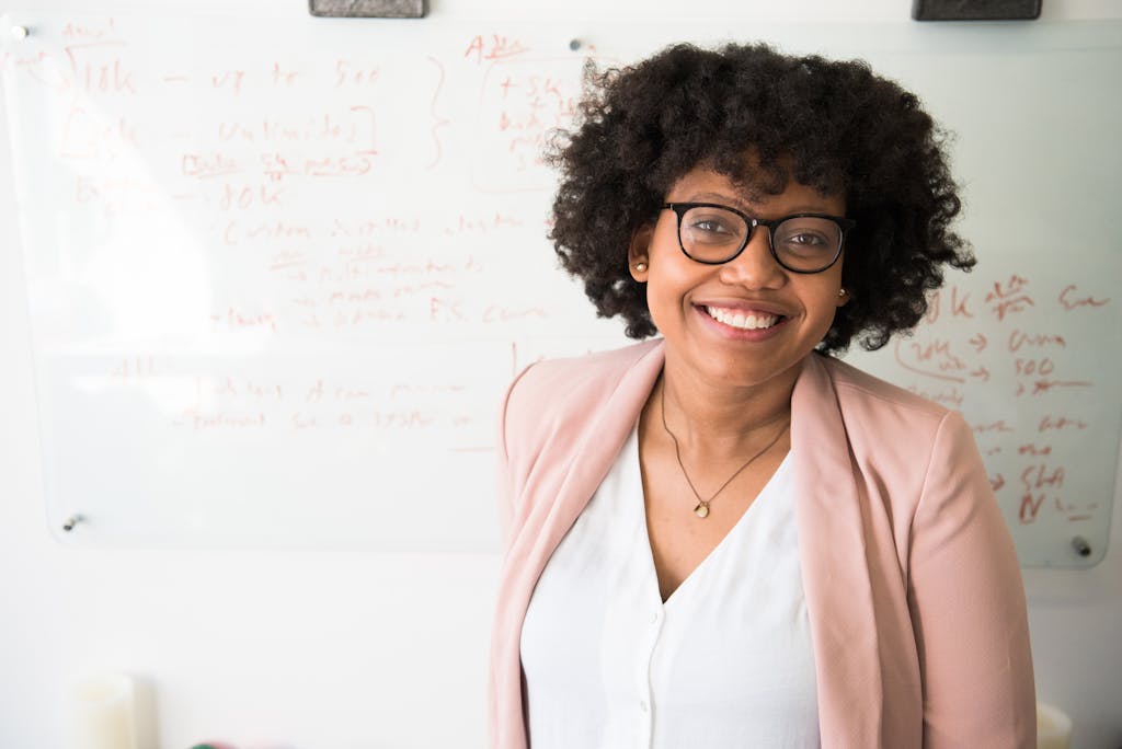 Smiling businesswoman with glasses and afro hairstyle in an office setting. Photographed by Hammer and Pixel - Hamilton Web Design & Digital Marketing Agency